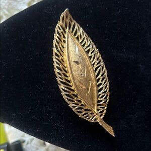 Vintage gold brooch with openwork details decorated with leaf engravings.